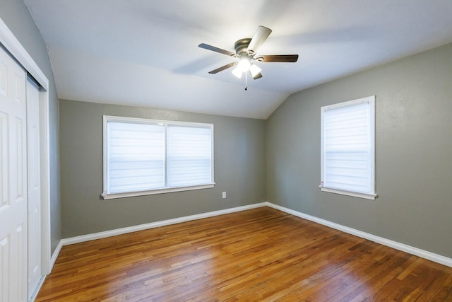 unfurnished bedroom with hardwood / wood-style flooring, lofted ceiling, ceiling fan, and multiple windows