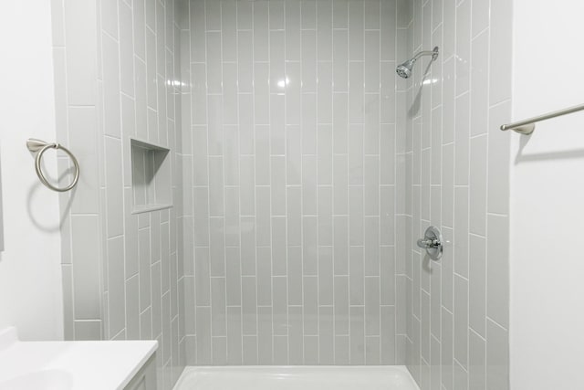 bathroom featuring a tile shower and vanity