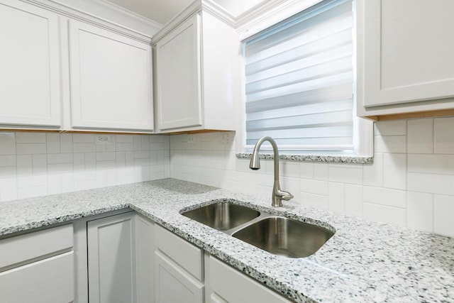 kitchen featuring sink, backsplash, light stone countertops, and white cabinets