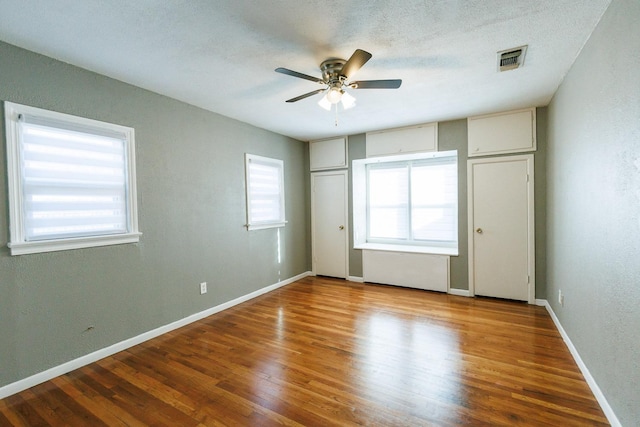 unfurnished bedroom featuring a textured ceiling, wood-type flooring, and ceiling fan