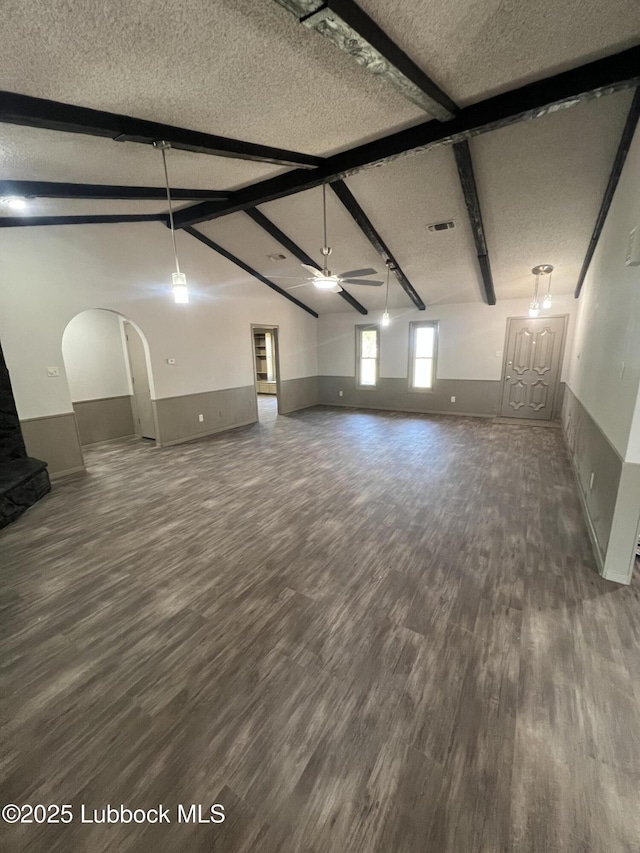 3535 W State Rd 300, Levelland, TX 79336 - unfurnished living room with a textured ceiling, wood finished floors, ceiling fan, a wainscoted wall, and arched walkways