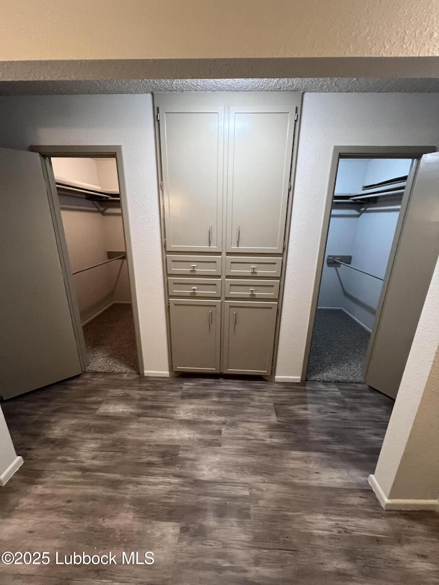 3535 W State Rd 300, Levelland, TX 79336 - unfurnished bedroom with dark wood-style flooring, a textured wall, and multiple closets