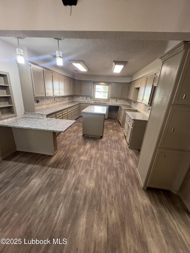 3535 W State Rd 300, Levelland, TX 79336 - kitchen with gray cabinetry, dark wood finished floors, a textured ceiling, light stone counters, and decorative backsplash