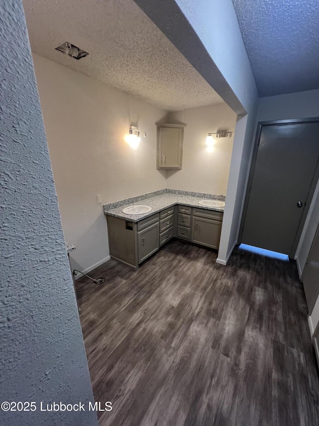 3535 W State Rd 300, Levelland, TX 79336 - kitchen with a textured ceiling, dark wood-style flooring, a textured wall, gray cabinets, and light stone countertops