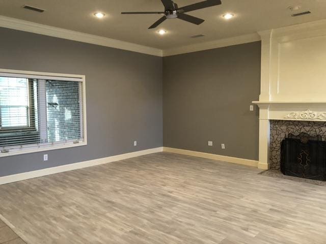 unfurnished living room featuring ornamental molding, light wood-type flooring, and ceiling fan