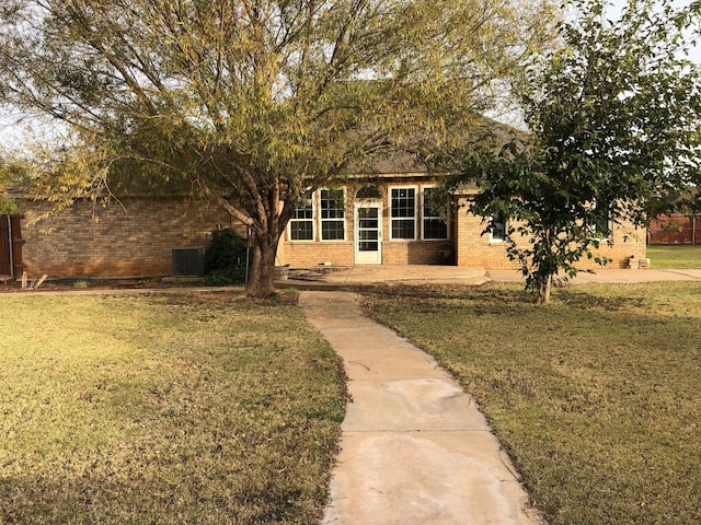 view of front of home with central AC, a patio area, and a front lawn