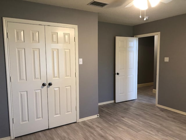 unfurnished bedroom with ceiling fan, wood-type flooring, and a closet