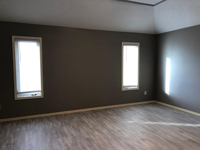 spare room with hardwood / wood-style flooring and vaulted ceiling