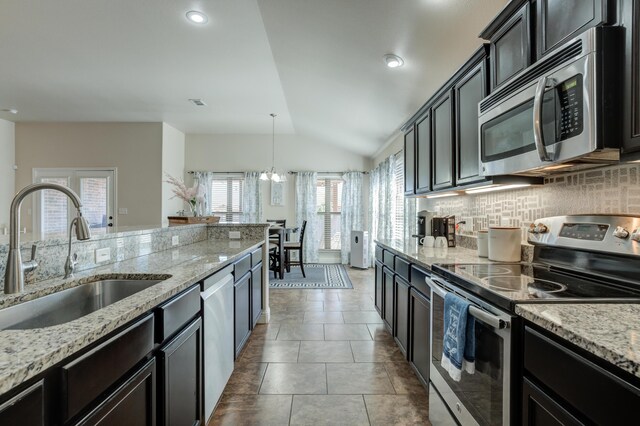 9207 Trenton Ave, Lubbock, TX 79424 - kitchen with appliances with stainless steel finishes, vaulted ceiling, decorative backsplash, light stone counters, and pendant lighting