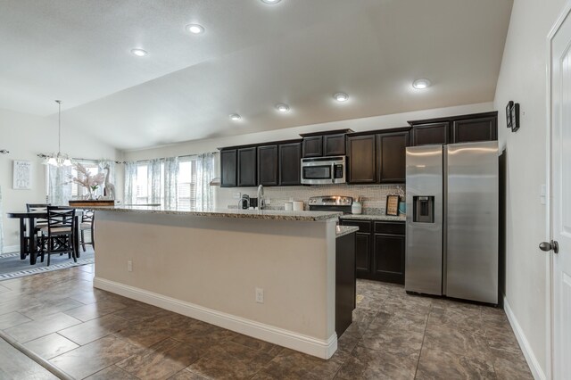 9207 Trenton Ave, Lubbock, TX 79424 - kitchen featuring appliances with stainless steel finishes, lofted ceiling, an island with sink, tasteful backsplash, and light stone counters