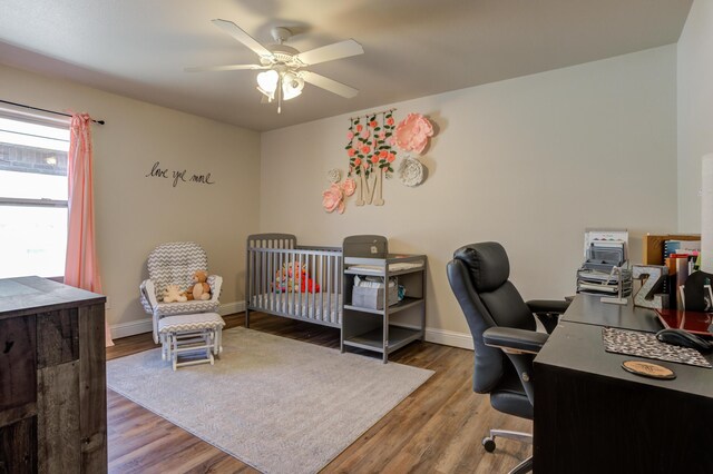 9207 Trenton Ave, Lubbock, TX 79424 - bedroom featuring an office area, wood finished floors, a crib, and a ceiling fan