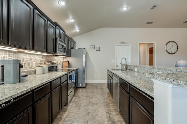 9207 Trenton Ave, Lubbock, TX 79424 - kitchen featuring stainless steel appliances, vaulted ceiling, backsplash, light stone counters, and light stone finish floors