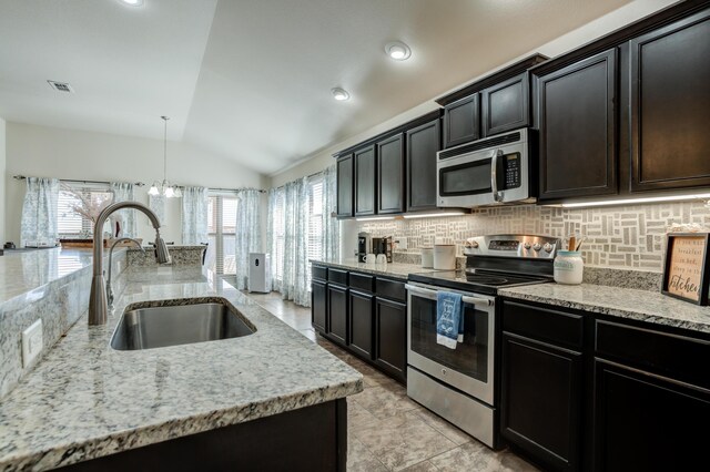 9207 Trenton Ave, Lubbock, TX 79424 - kitchen featuring stainless steel appliances, lofted ceiling, tasteful backsplash, light stone countertops, and a chandelier