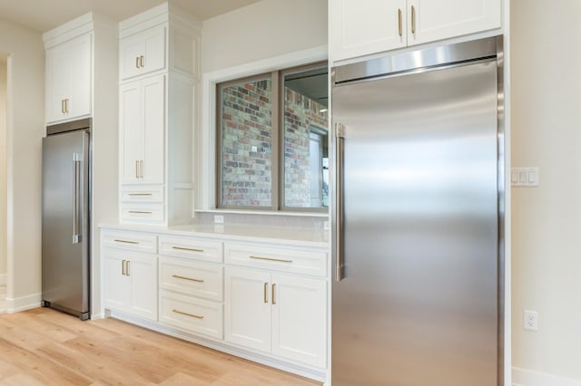 kitchen with high quality fridge, stainless steel built in fridge, light hardwood / wood-style flooring, and white cabinets