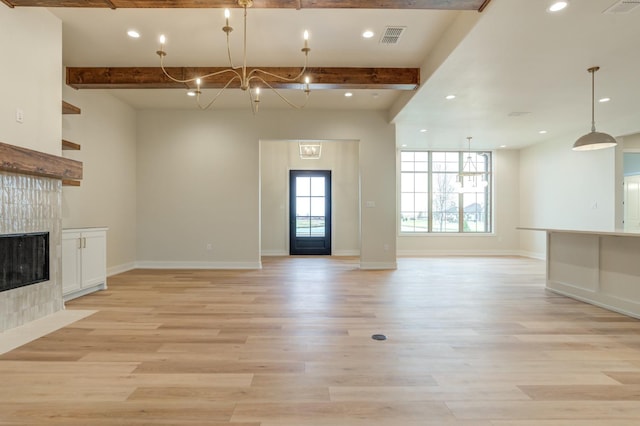 unfurnished living room featuring beamed ceiling, a chandelier, a fireplace, and light hardwood / wood-style floors