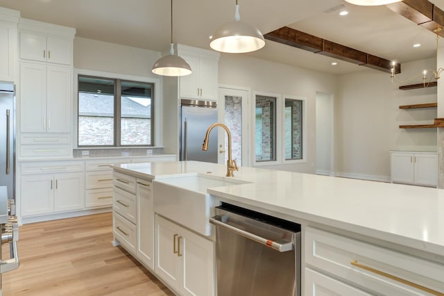 kitchen with sink, pendant lighting, white cabinetry, appliances with stainless steel finishes, and beamed ceiling