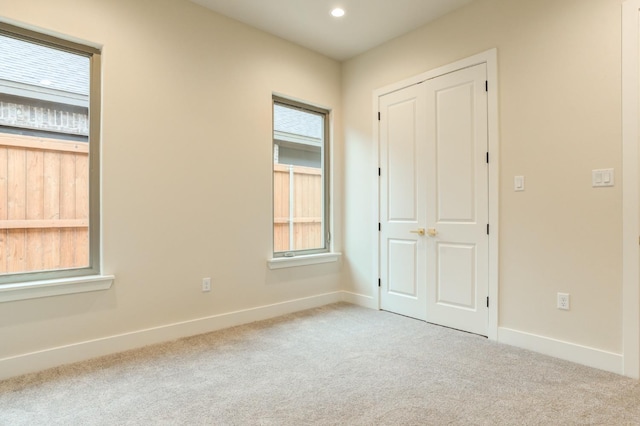 unfurnished room featuring a wealth of natural light and light colored carpet