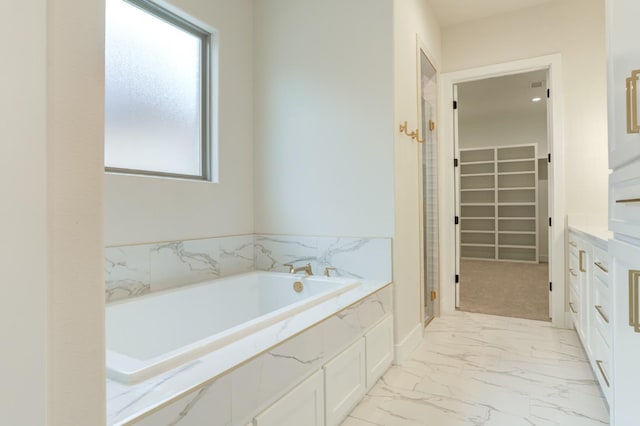 bathroom with a tub to relax in and a healthy amount of sunlight