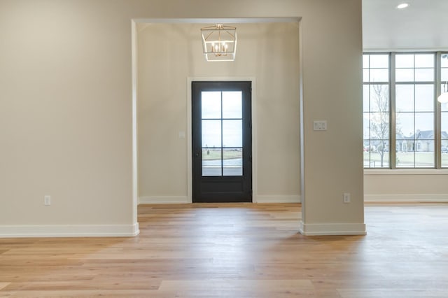 foyer entrance with an inviting chandelier, a wealth of natural light, and light wood-type flooring