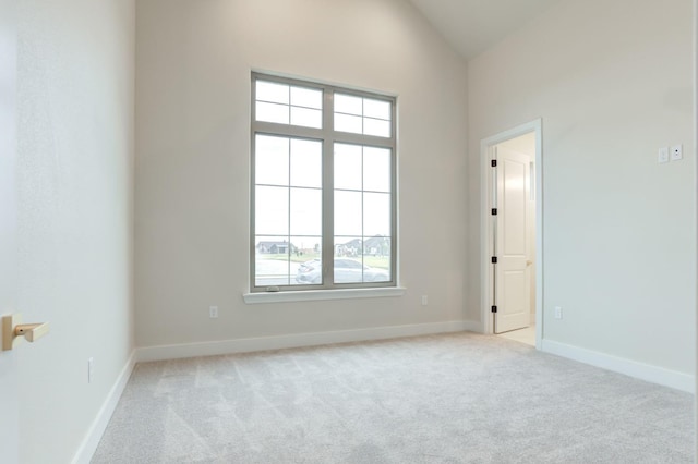 carpeted empty room featuring lofted ceiling