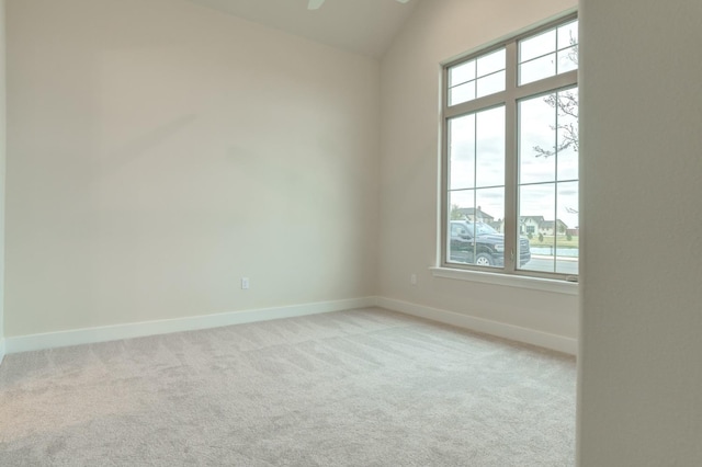 spare room featuring vaulted ceiling and light carpet