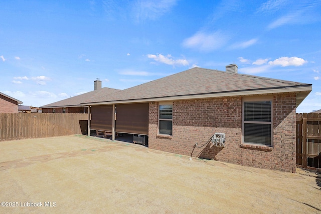 11104 Englewood Ave, Lubbock, TX 79424 - back of house featuring brick siding, a chimney, fence, and roof with shingles