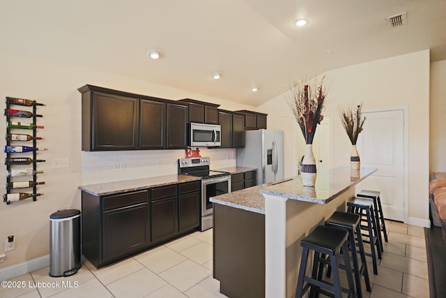 11104 Englewood Ave, Lubbock, TX 79424 - kitchen featuring lofted ceiling, light stone countertops, visible vents, a kitchen bar, and stainless steel appliances