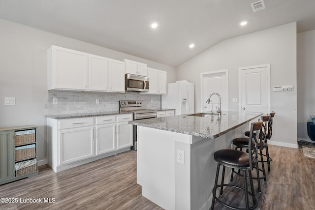 3222 Waverly Ave, Lubbock, TX 79407 - kitchen with appliances with stainless steel finishes, backsplash, a kitchen breakfast bar, vaulted ceiling, and white cabinetry