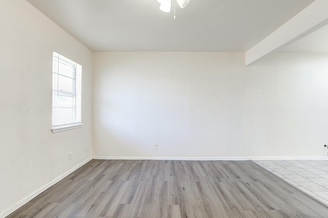 spare room with beamed ceiling and light hardwood / wood-style floors