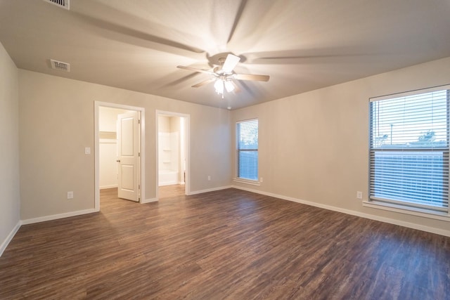 unfurnished bedroom featuring ceiling fan, ensuite bathroom, dark hardwood / wood-style floors, and multiple windows