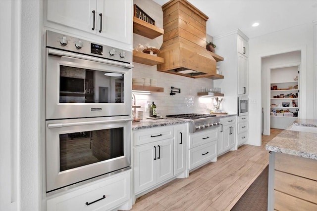 kitchen featuring light stone counters, stainless steel appliances, and white cabinets