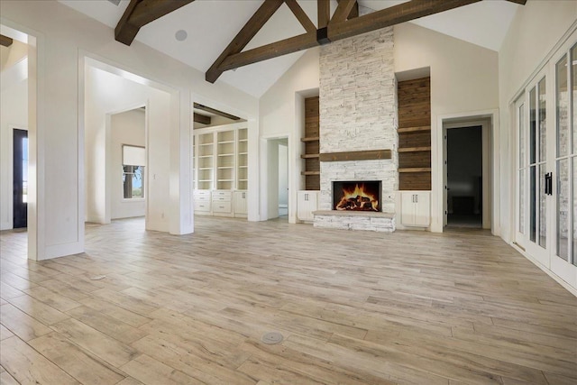 unfurnished living room with a fireplace, light hardwood / wood-style flooring, high vaulted ceiling, and beamed ceiling