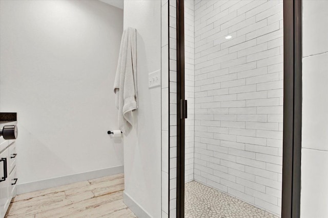 bathroom with hardwood / wood-style flooring and a shower with shower door