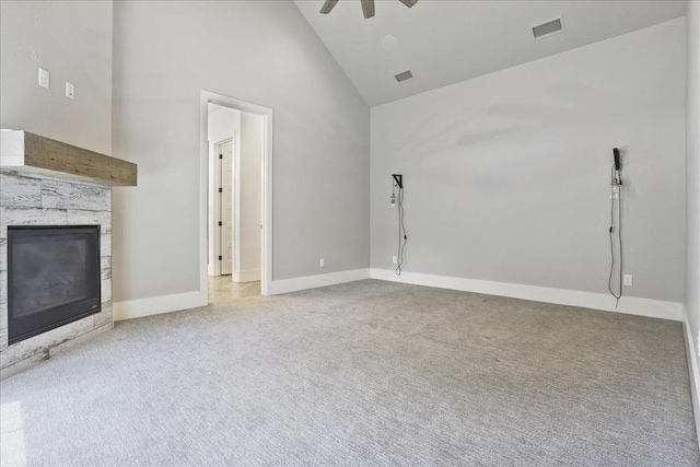 unfurnished living room featuring ceiling fan, light colored carpet, a stone fireplace, and high vaulted ceiling