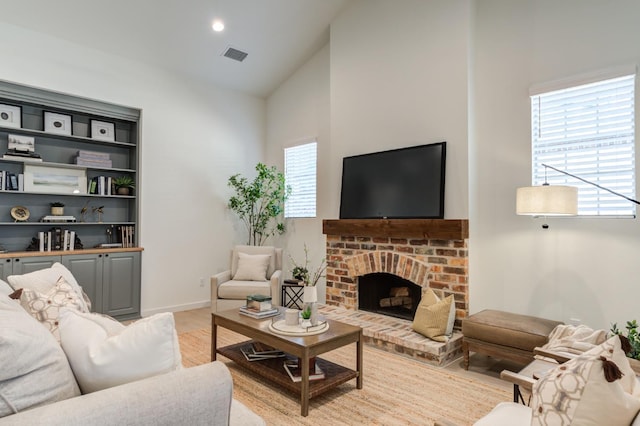 living room with vaulted ceiling, a brick fireplace, and light hardwood / wood-style floors