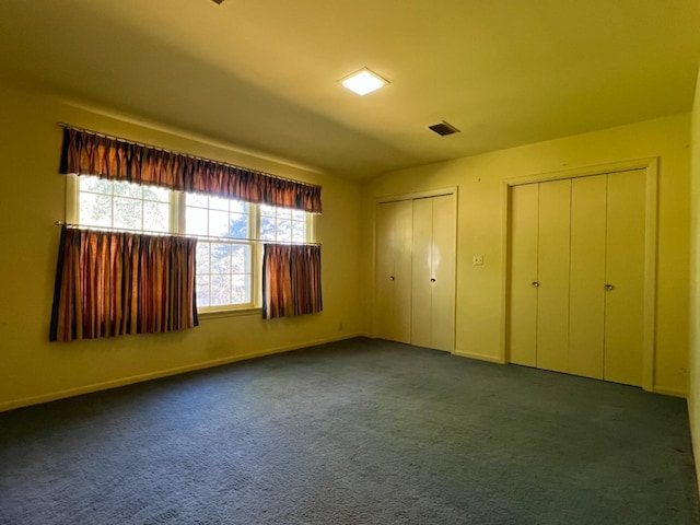 unfurnished bedroom with two closets and dark carpet