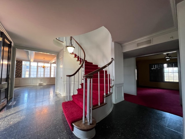 staircase with ceiling fan with notable chandelier