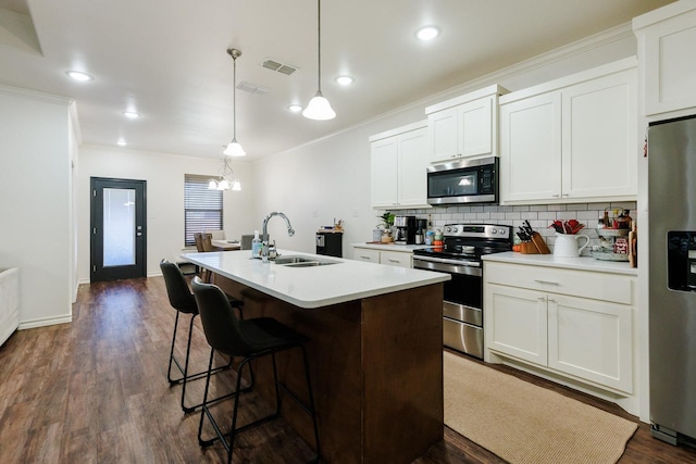 kitchen with pendant lighting, sink, appliances with stainless steel finishes, white cabinets, and a center island with sink