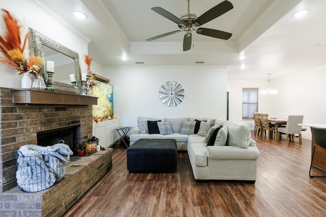 living room with hardwood / wood-style floors, ceiling fan, a raised ceiling, crown molding, and a brick fireplace