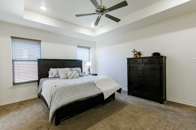 bedroom featuring a raised ceiling, ceiling fan, and carpet flooring