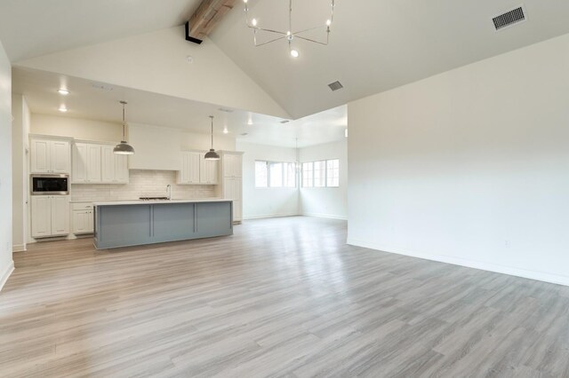 7615 52nd St, Lubbock, TX 79407 - kitchen featuring built in microwave, open floor plan, a chandelier, beam ceiling, and light wood finished floors