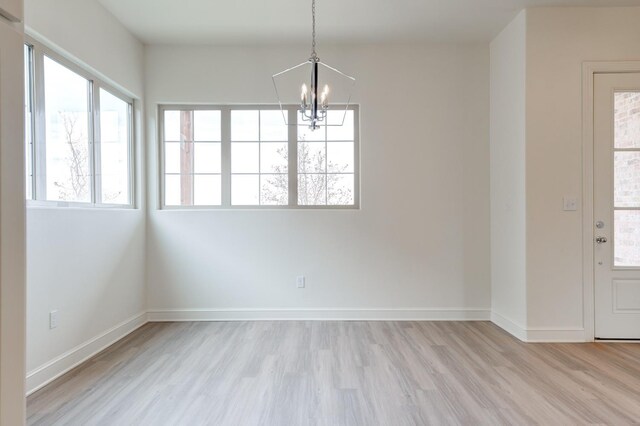 7615 52nd St, Lubbock, TX 79407 - unfurnished dining area with a chandelier, light wood-style floors, and baseboards