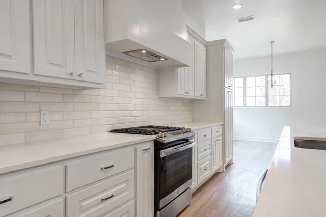 7615 52nd St, Lubbock, TX 79407 - kitchen featuring stainless steel range with gas stovetop, custom exhaust hood, tasteful backsplash, white cabinets, and light wood finished floors