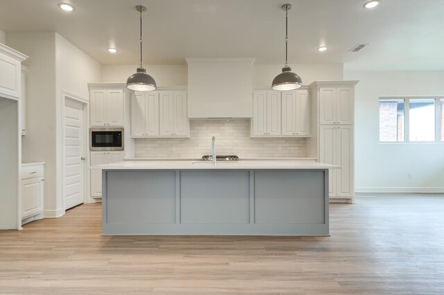 7615 52nd St, Lubbock, TX 79407 - kitchen with stainless steel microwave, light countertops, backsplash, light wood-type flooring, and recessed lighting