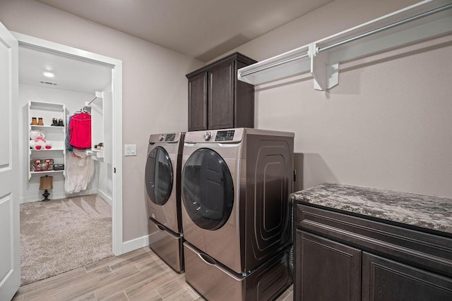 washroom featuring cabinets, separate washer and dryer, and light hardwood / wood-style flooring