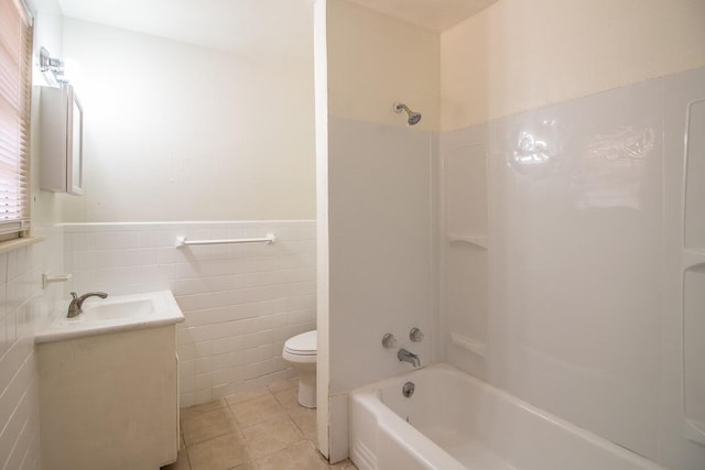 full bathroom featuring tile patterned floors, toilet, tub / shower combination, tile walls, and vanity