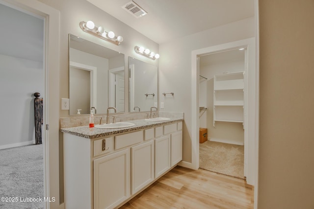2933 Abbeville Ave, Wolfforth, TX 79382 - bathroom featuring double vanity, a walk in closet, and wood finished floors
