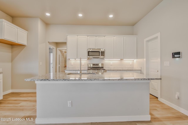 2933 Abbeville Ave, Wolfforth, TX 79382 - kitchen with stainless steel appliances, white cabinetry, light stone countertops, light wood-type flooring, and recessed lighting