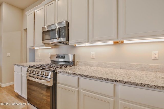 2933 Abbeville Ave, Wolfforth, TX 79382 - kitchen featuring stainless steel appliances, light wood-style floors, light stone counters, and white cabinets
