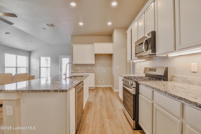 2933 Abbeville Ave, Wolfforth, TX 79382 - kitchen featuring appliances with stainless steel finishes, light wood-style floors, a ceiling fan, a center island with sink, and lofted ceiling